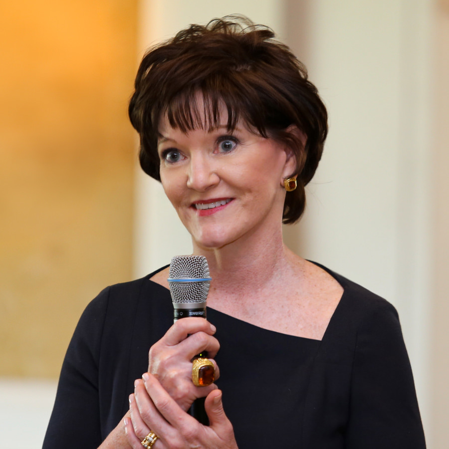 Beth Sanders Moore in a navy dress standing in the audience and holding a mic as moderator of a Ted Kennedy Jr. cancer survivorship Q&A.